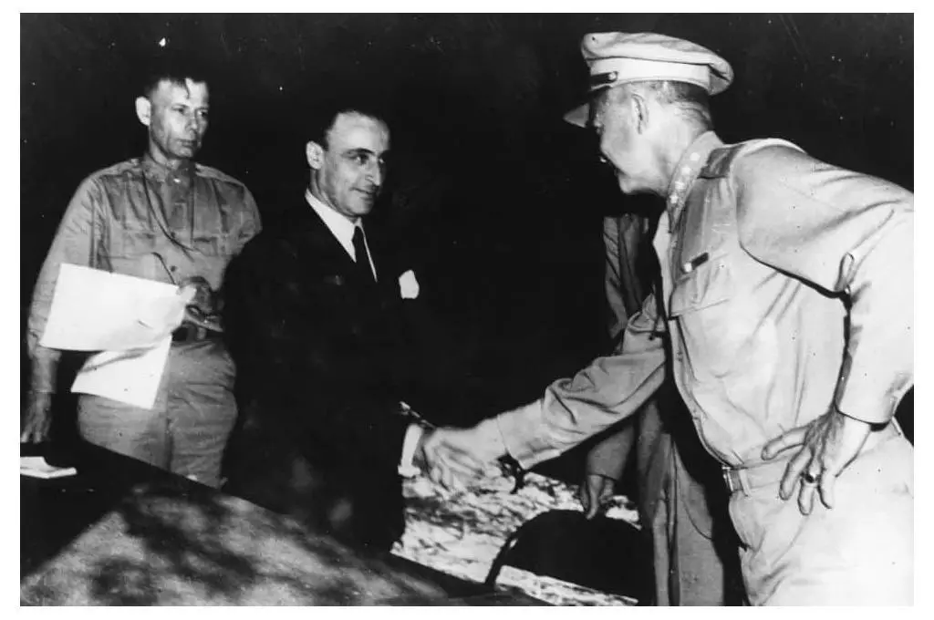 General Giuseppe Castellano, in civilian attire, shakes hands with General Eisenhower after signing the armistice.